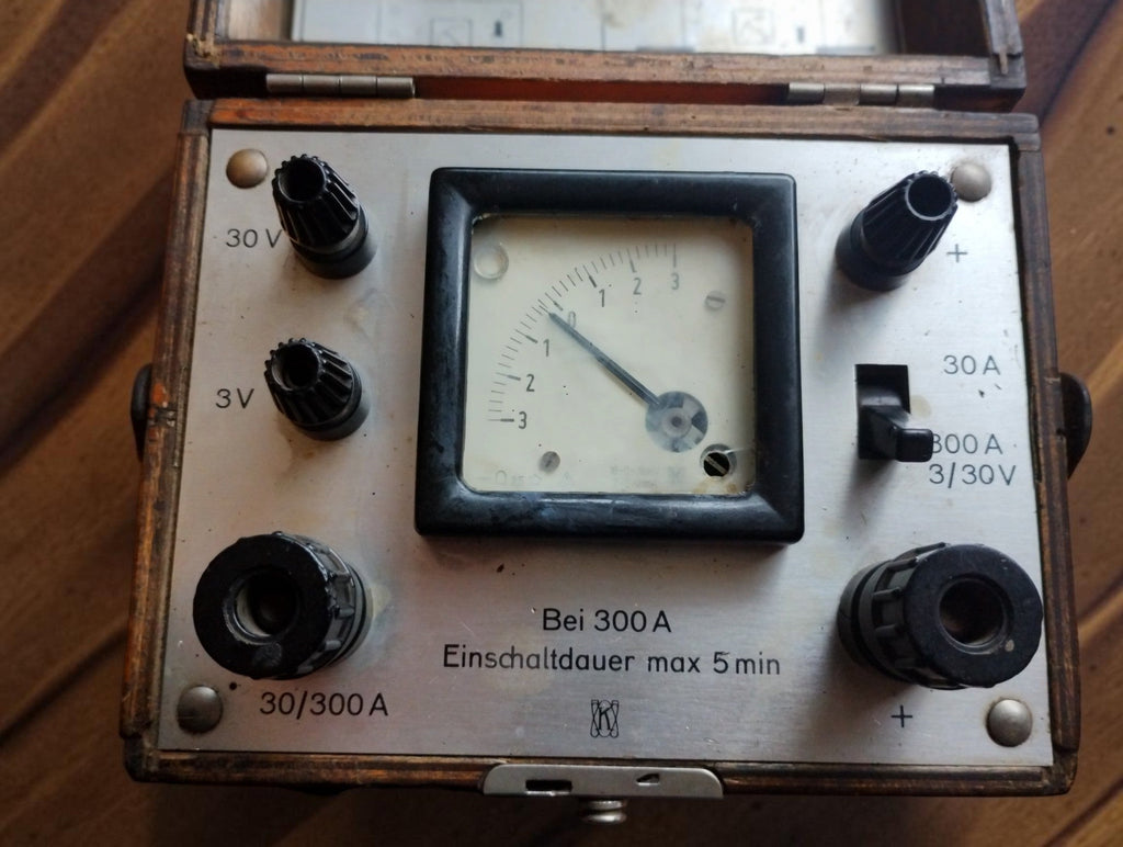 Opposite view of the vintage DC meter panel, showing the analog scale, range selector, terminals and German operating-time warning.
