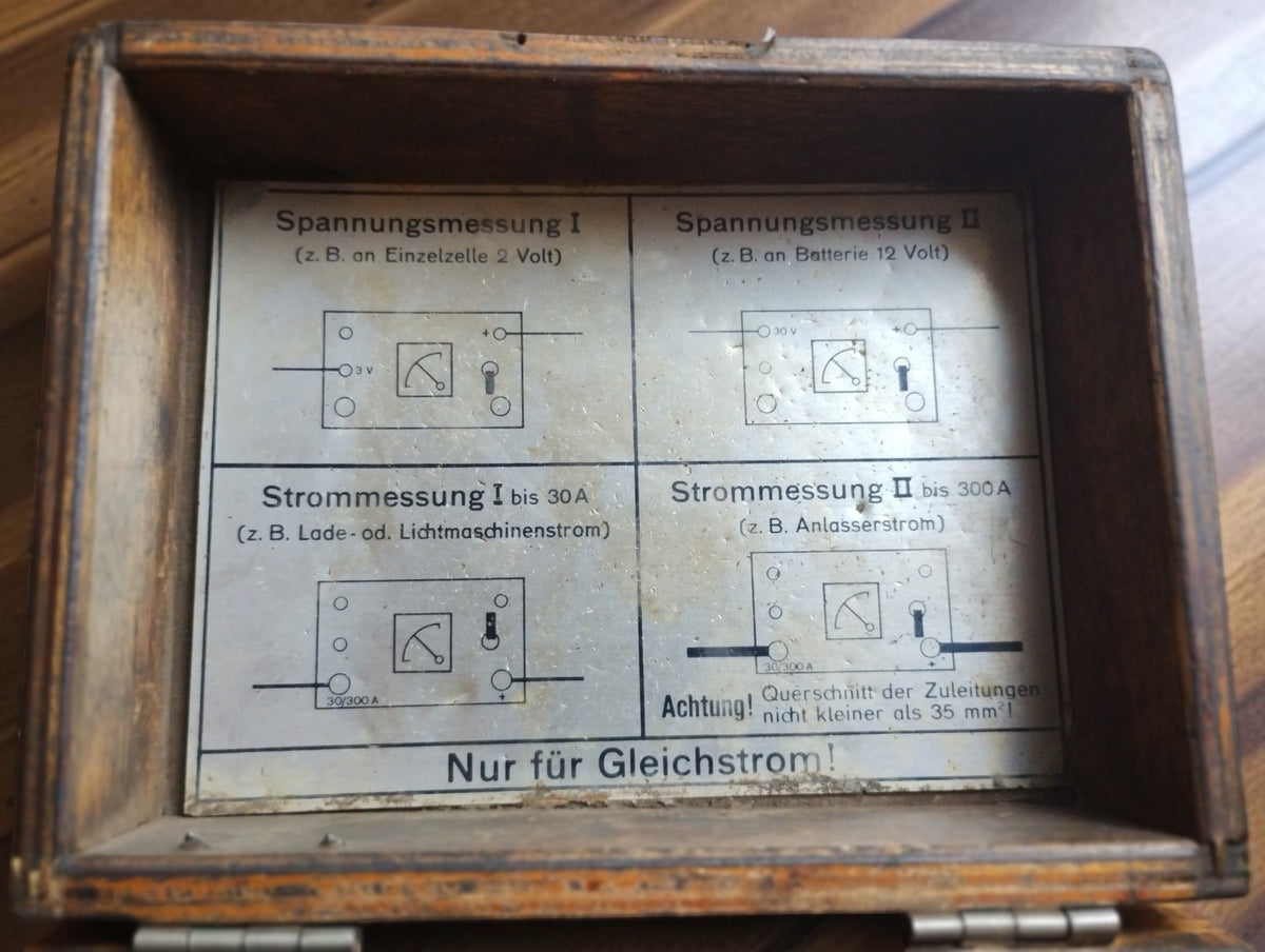 German wiring diagrams inside the wooden lid for DC voltage and current measurements, including starter and generator applications.
