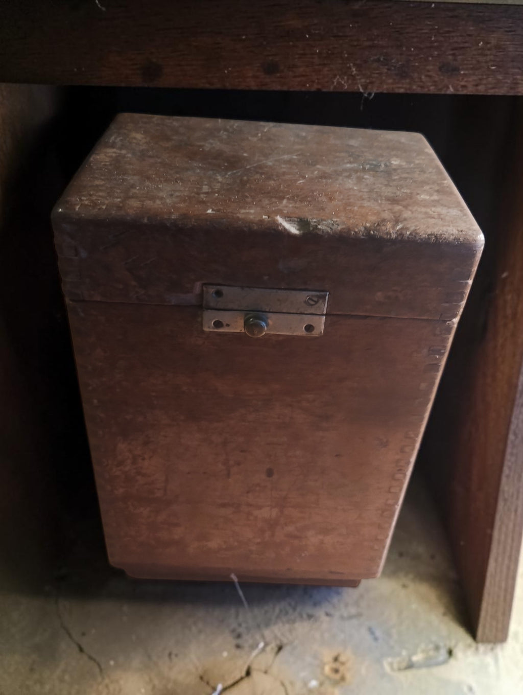 Closed wooden case of an antique German insulation tester, showing the metal latch and age-related wear.
