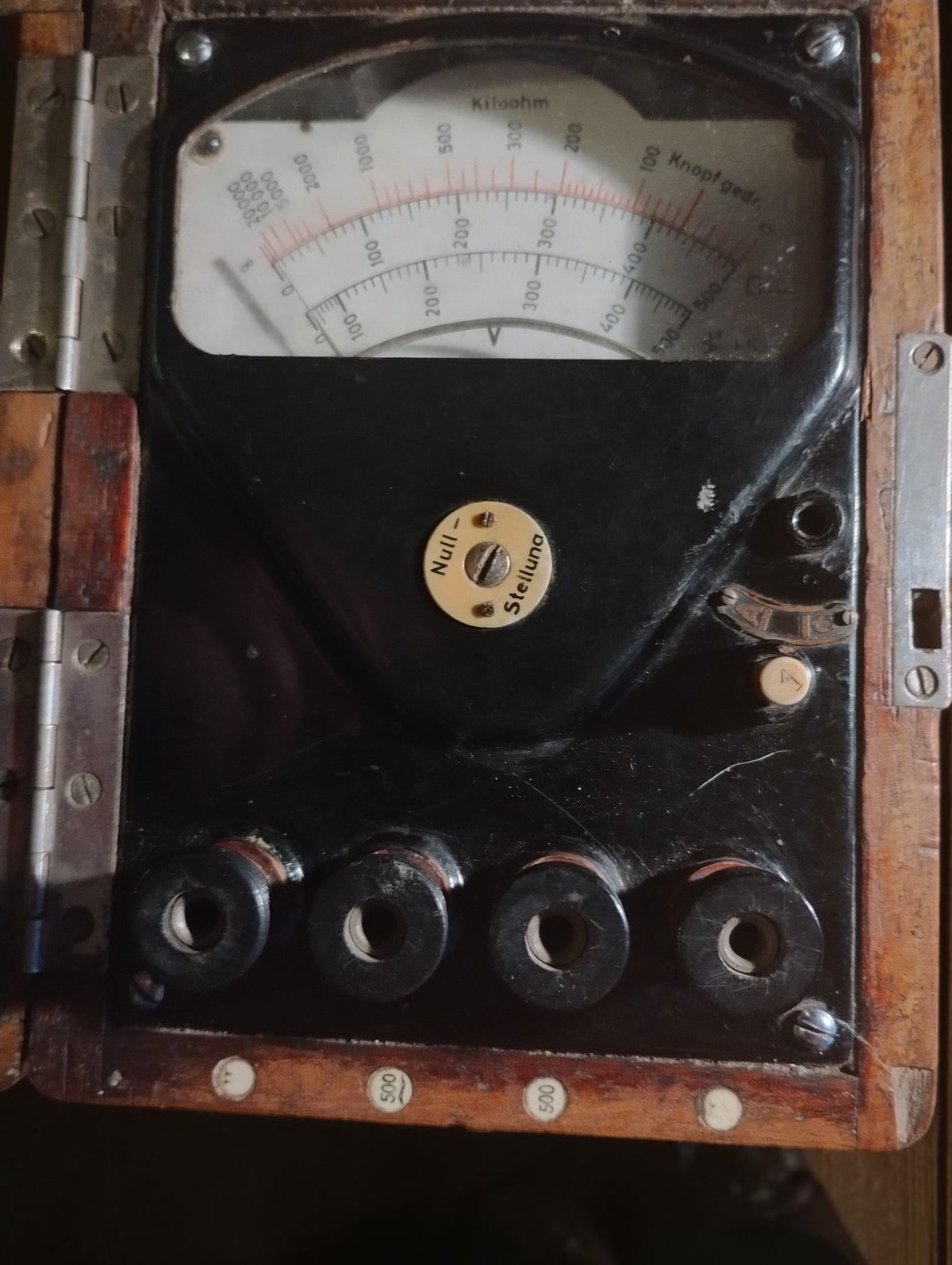 Antique German insulation tester in its open wooden case, with an analog dial, zero adjustment, and four connection terminals.
