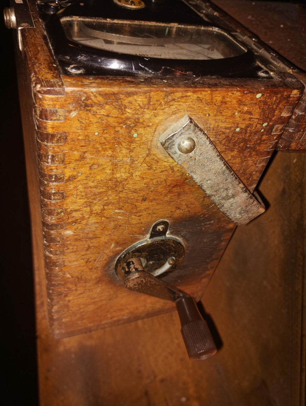 Side of the wooden insulation tester case, showing dovetail joints, the crank fitting, and a worn leather carrying strap.
