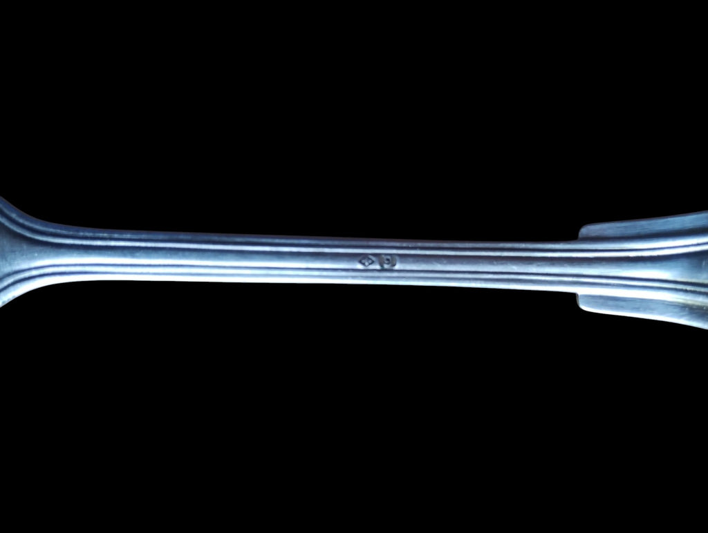 Close-up of a small indistinct stamp on the back of the vintage spoon's stem
