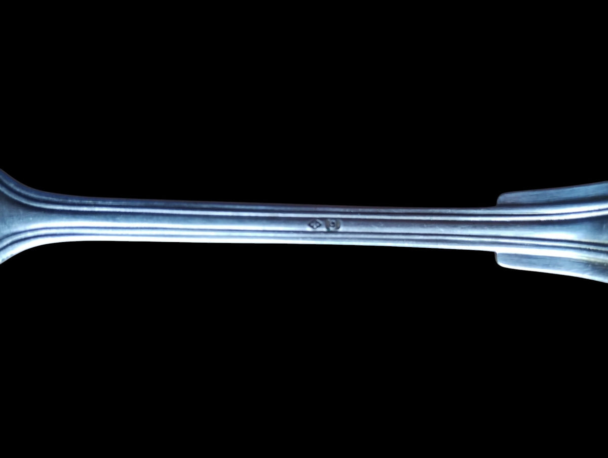 Close-up of a small indistinct stamp on the back of the vintage spoon's stem
