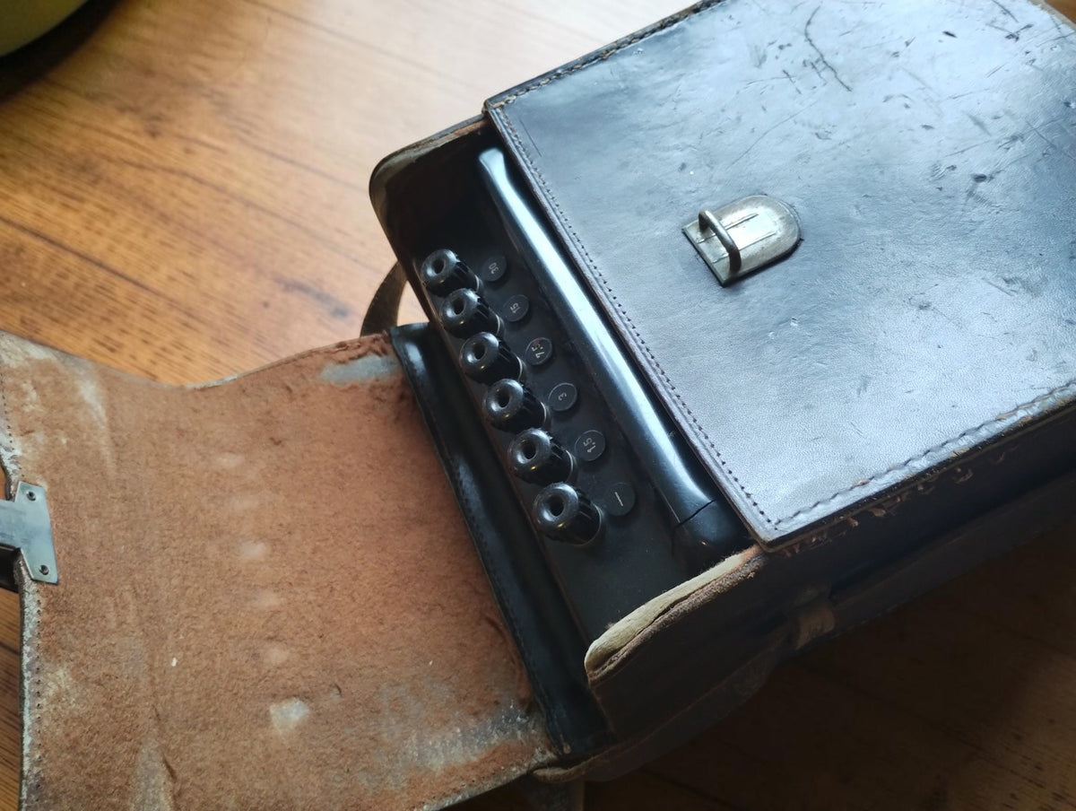 Open brown leather carrying case with the Hartmann & Braun milliammeter and its terminals visible
