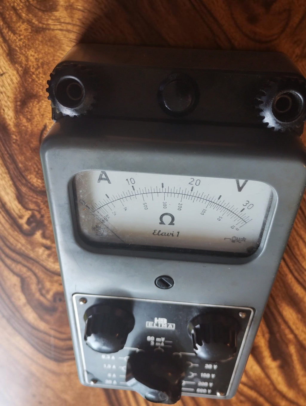 Angled view of the ELIMA Elavi 1 multimeter showing the analog dial, control knobs and connection terminals
