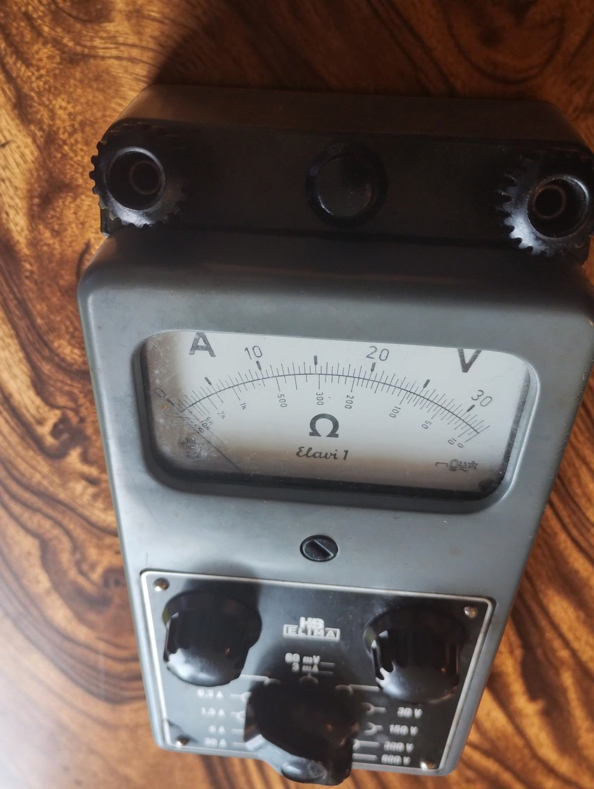 Angled view of the ELIMA Elavi 1 multimeter showing the analog dial, control knobs and connection terminals
