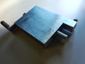 Metal hinge filing jig viewed diagonally from above, showing the crank, recessed corner and surface wear.