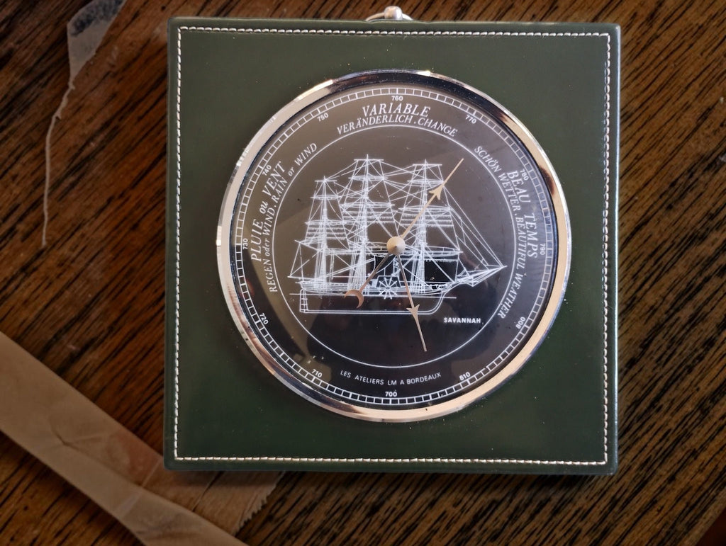 Savannah ship barometer with a dark dial, silver-tone rim and square green surround with white stitching.

