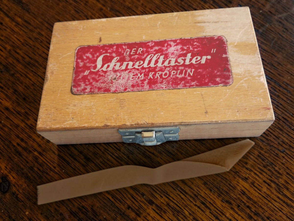 Closed wooden case with a worn red Der Schnelltaster System Kroplin label and metal clasp.
