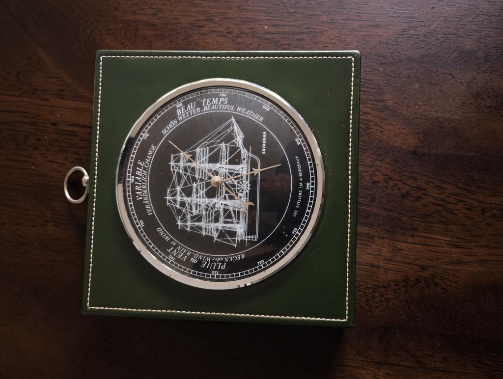 Full view of the Savannah ship barometer on dark wood, with its green square surround and hanging ring.
