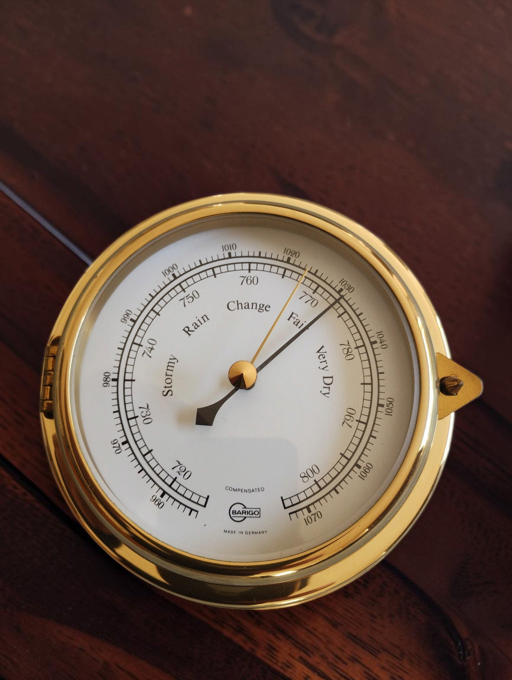 BARIGO nautical barometer with a white English dial, black pointer and polished gold-tone porthole-style case.
