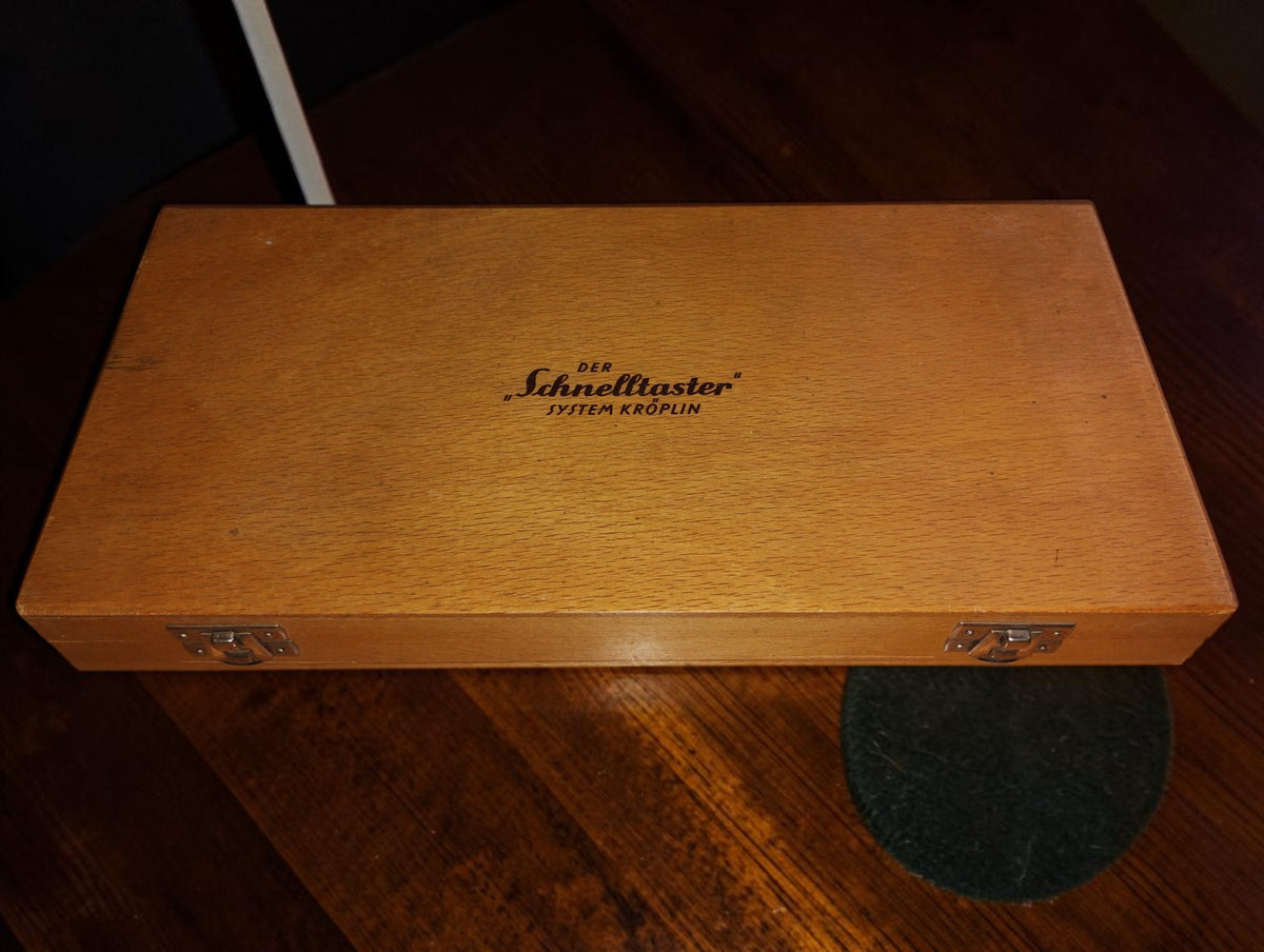 Closed wooden case with DER Schnelltaster SYSTEM KRÖPLIN branding and two metal clasps
