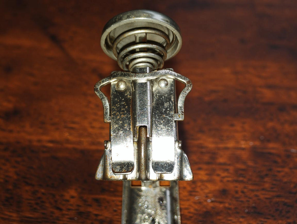 Detail van het metalen mechanisme en de veer onder de drukknop
