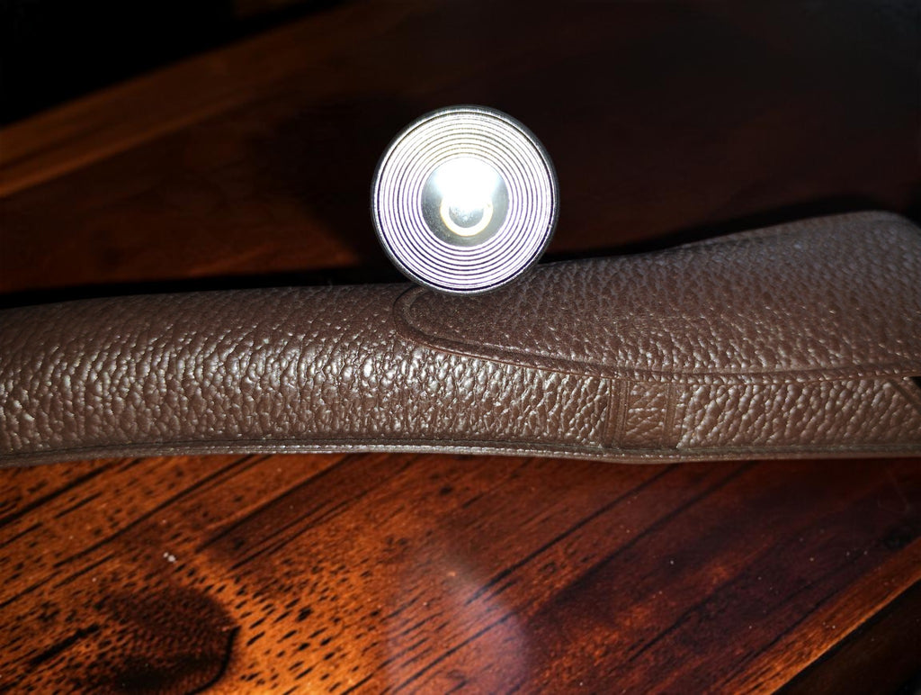 Detail van het ronde optische uiteinde van de vintage zakmicroscoop boven het bruine etui
