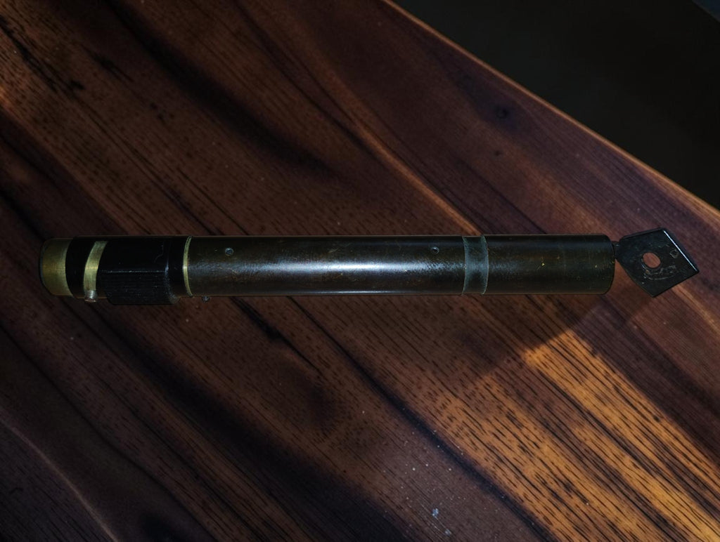 Zijaanzicht van de vintage zakmicroscoop met ronde opening in het scharnierende kijkplaatje
