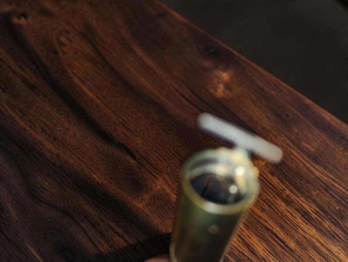 Detail van het optische uiteinde van de vintage zakmicroscoop met het kijkplaatje erboven
