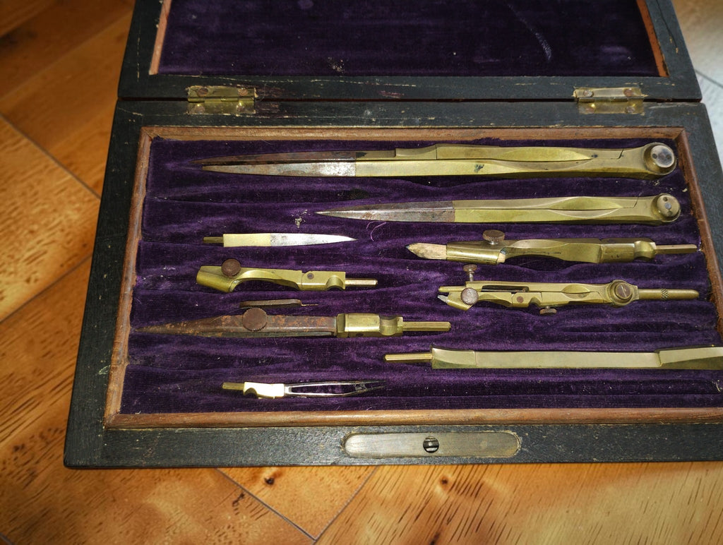 Detail van vintage passers en tekenonderdelen met goudkleurige en staalkleurige delen in de houten kist
