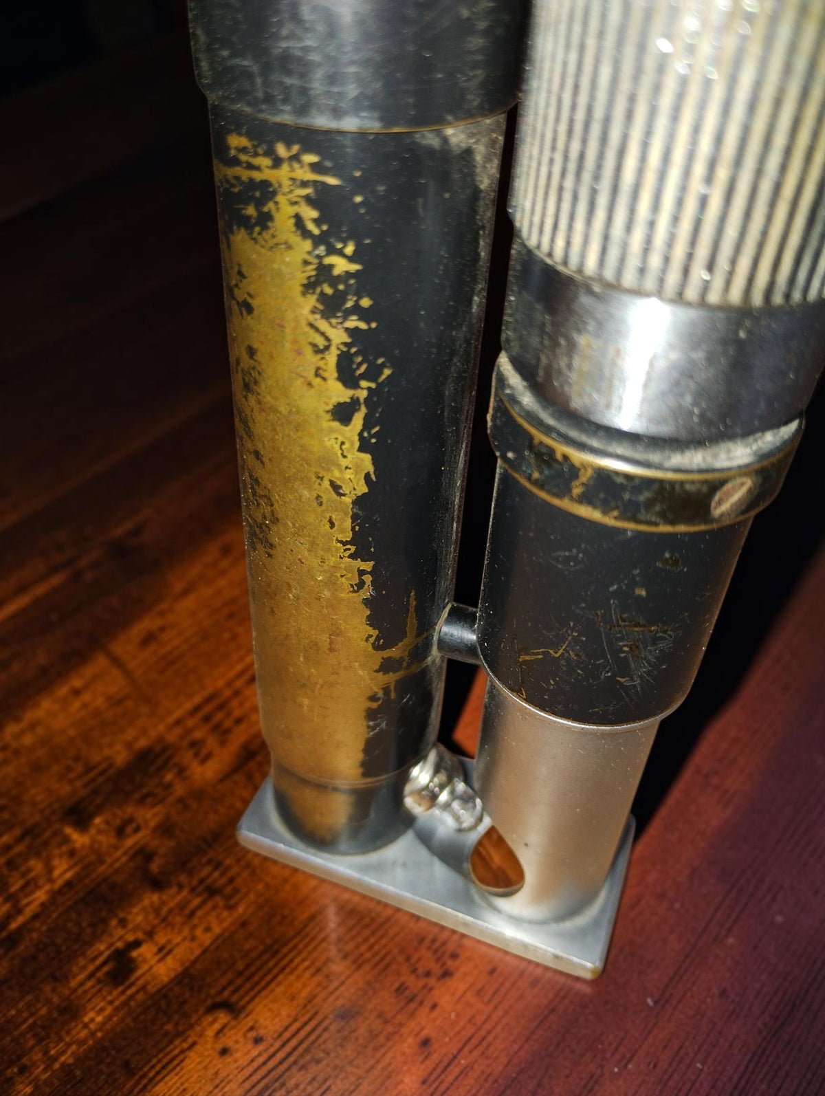 Close-up of the microscope and lamp cylinder showing worn black paint and exposed yellow metal.
