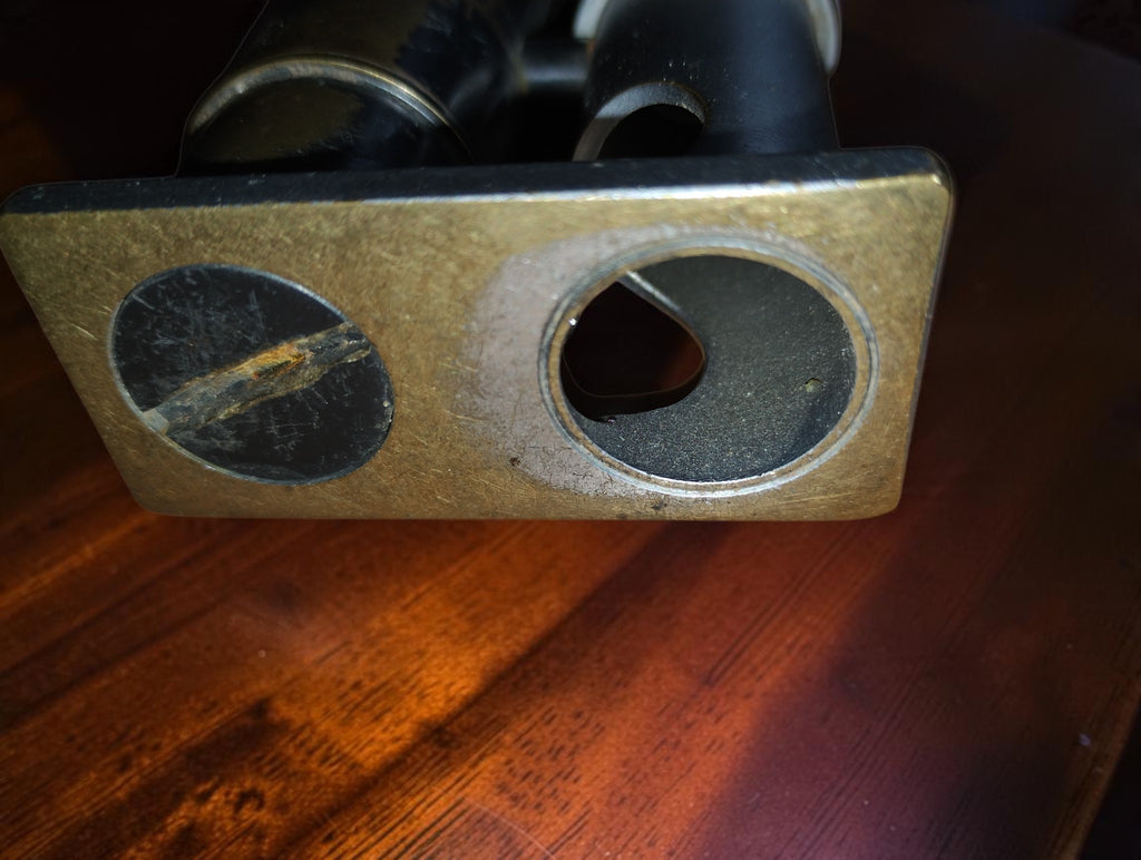Underside of the microscope base showing a circular opening and a large slotted screw.
