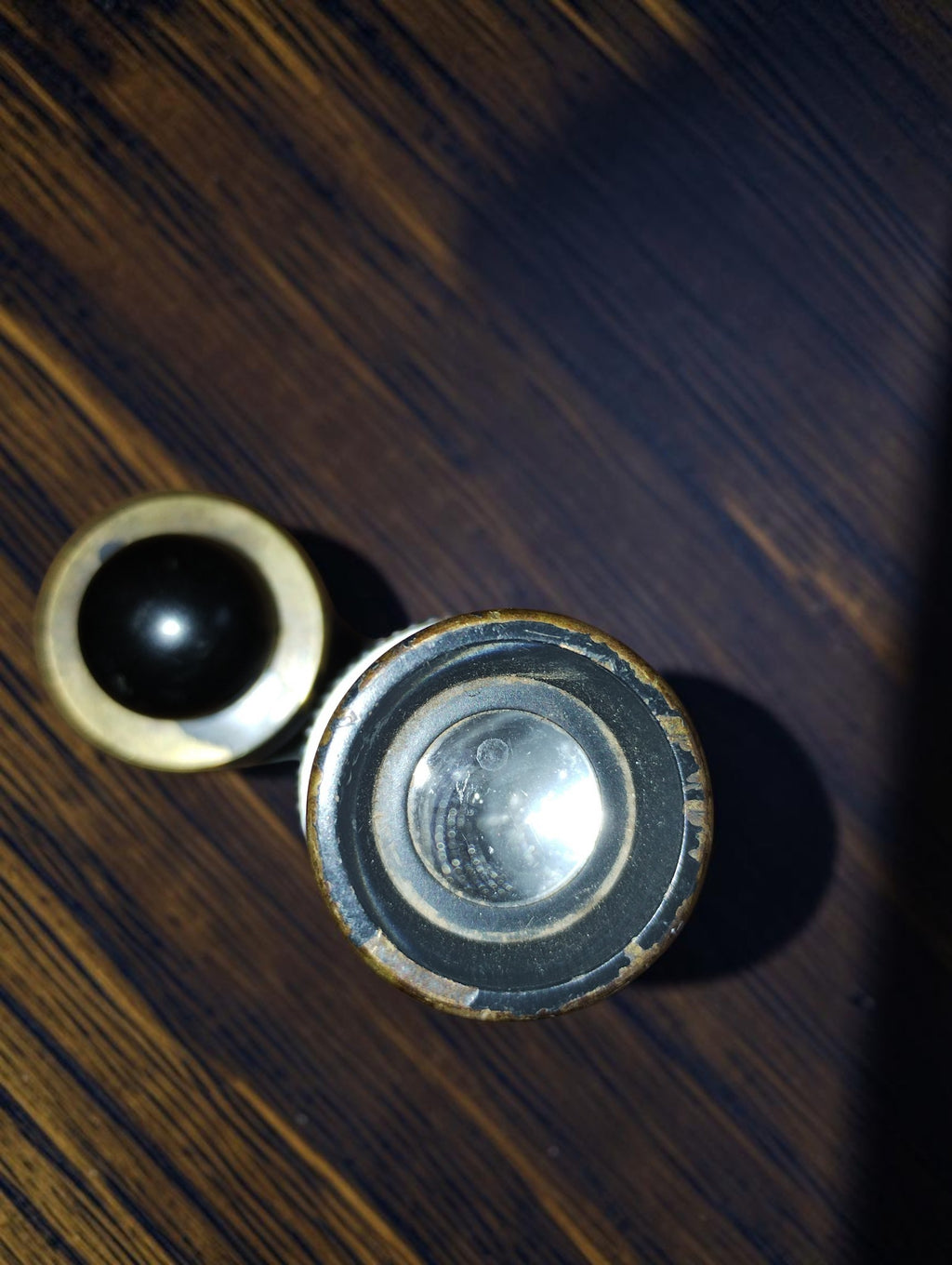 Top view of the inspection microscope showing the eyepiece lens and black button on the adjacent lighting housing.

