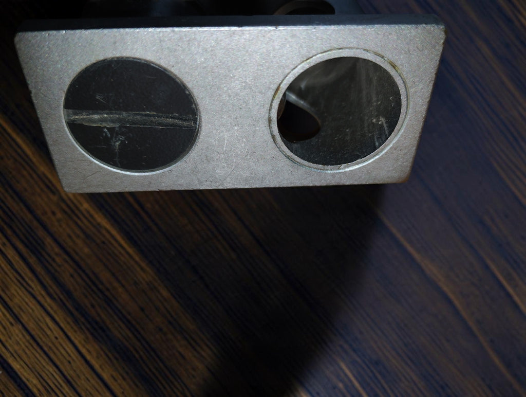 Underside of the vintage inspection microscope showing two circular openings in the rectangular metal base.
