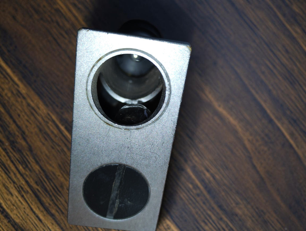 Close-up of the microscope base showing the optical opening and adjacent slotted cover.

