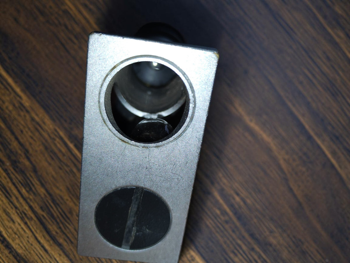 Close-up of the microscope base showing the optical opening and adjacent slotted cover.
