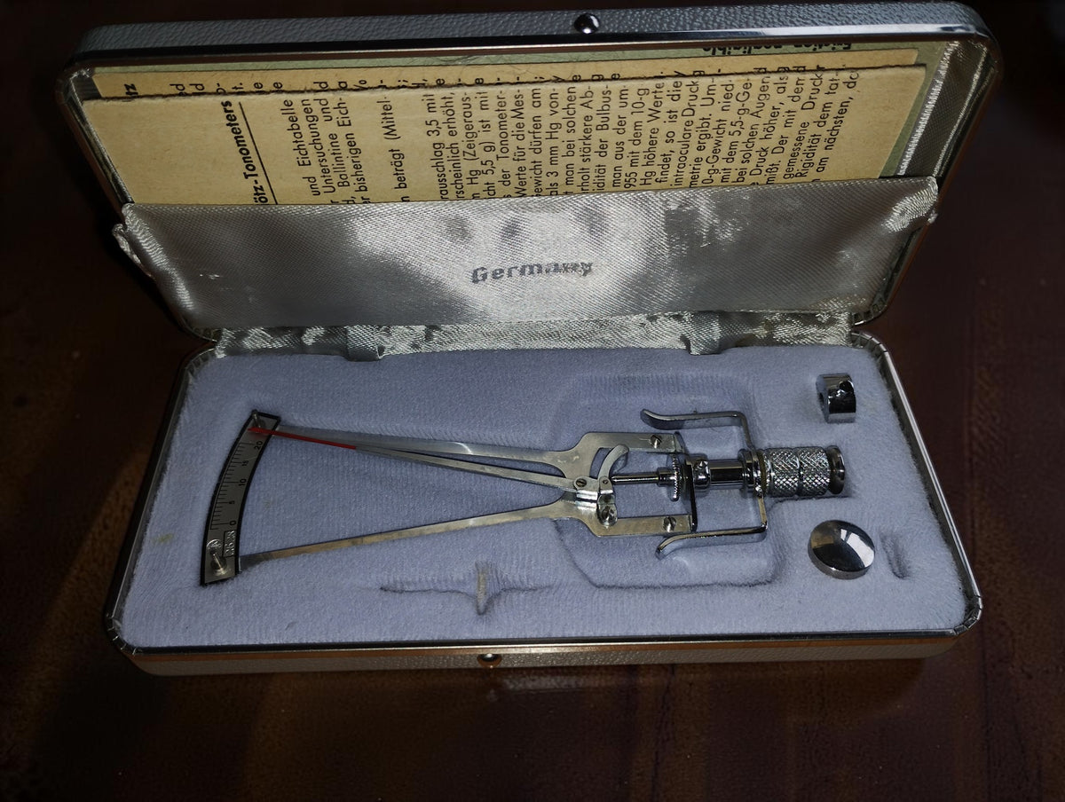 SK Schiötz tonometer in its open fitted case with additional weights and printed documentation.
