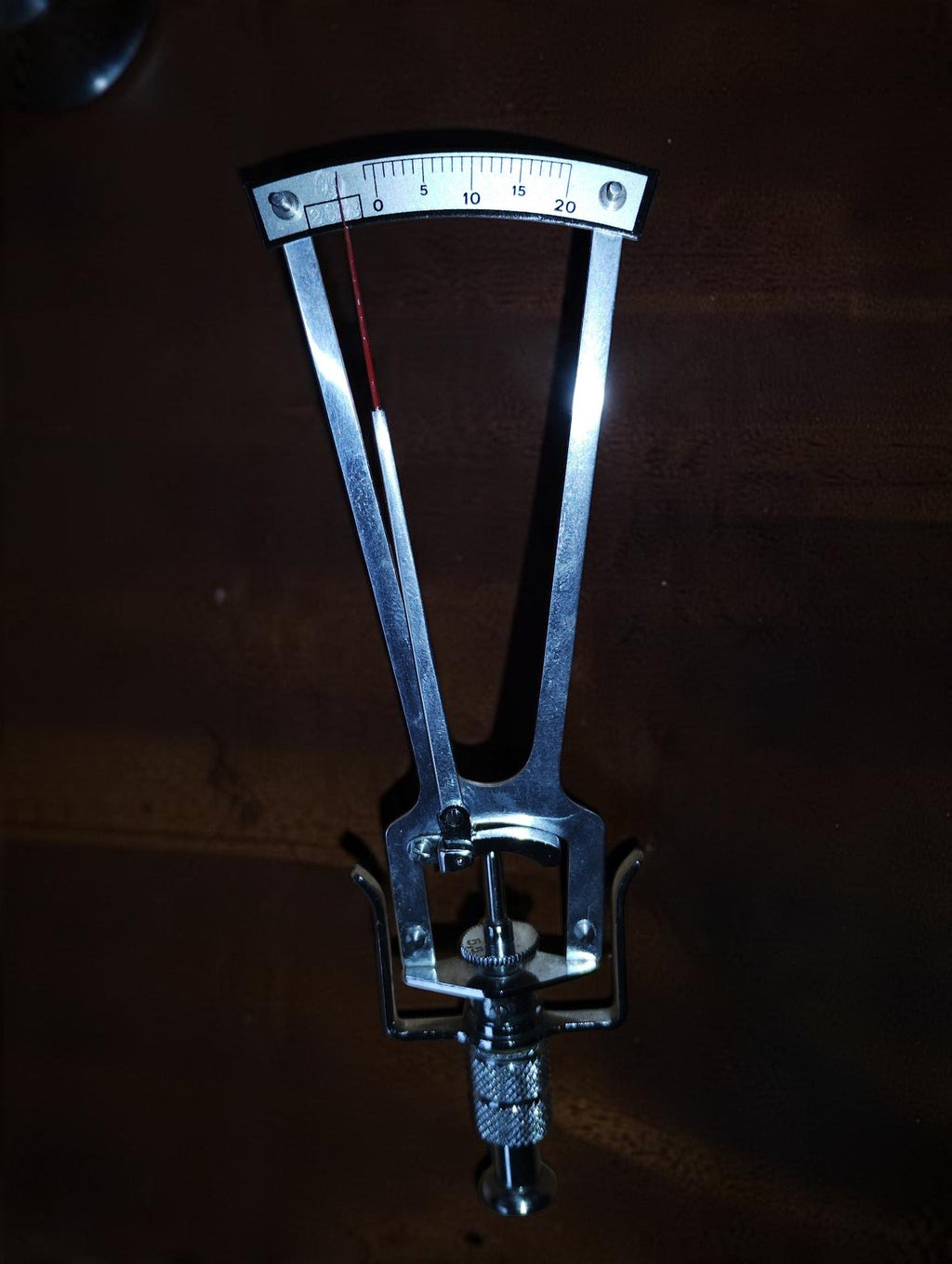 SK Schiötz tonometer showing its silver-coloured frame, red indicator needle and scale from 0 to 20.
