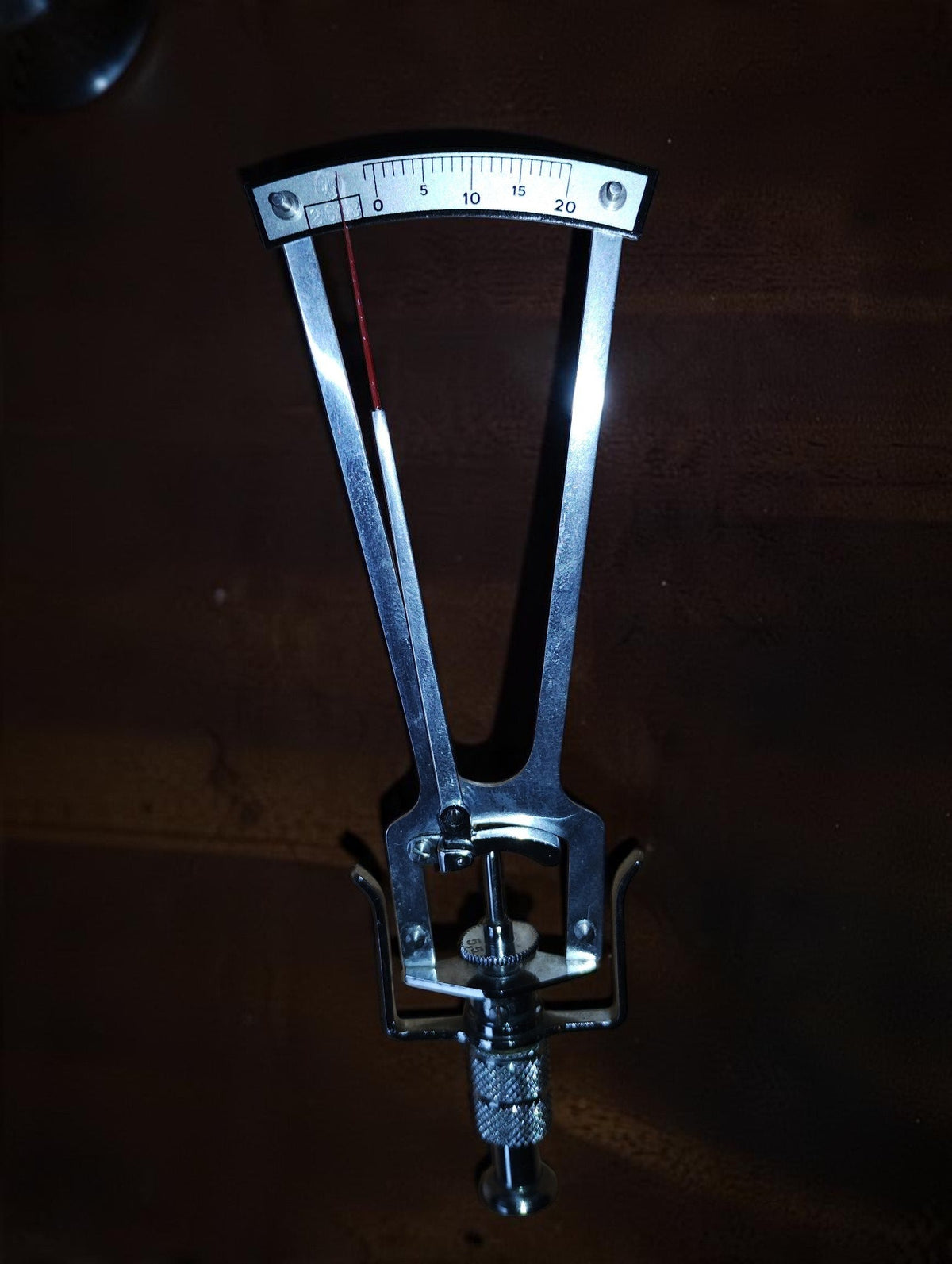 SK Schiötz tonometer showing its silver-coloured frame, red indicator needle and scale from 0 to 20.
