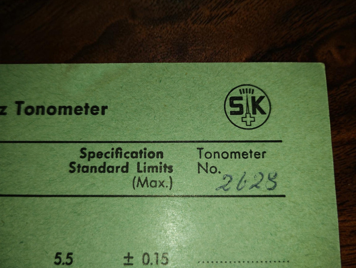 Close-up of the SK logo and handwritten tonometer number on the green certificate of accuracy.
