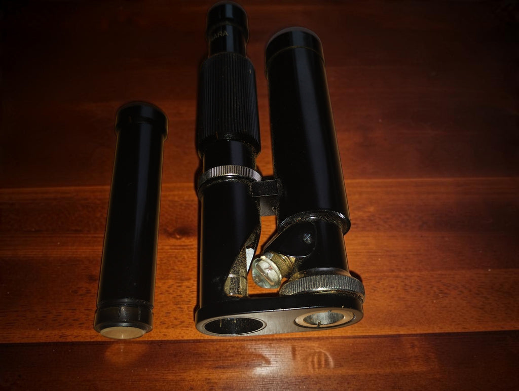 Ultra-Lomara pocket microscope showing its tilting mechanism and adjustment knobs, with a separate tube on the left.
