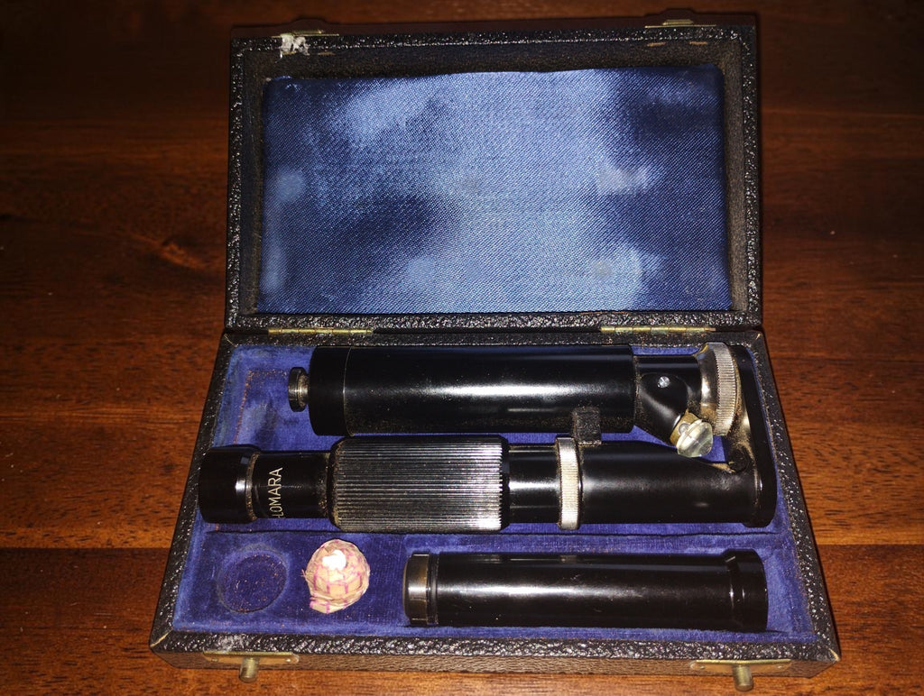 Ultra-Lomara pocket microscope and separate tube inside an open case with blue-purple lining.

