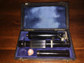 Ultra-Lomara pocket microscope and separate tube inside an open case with blue-purple lining.

