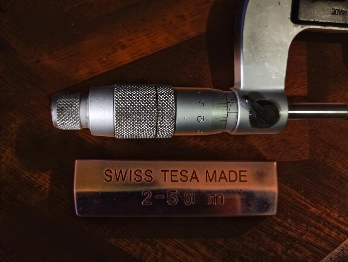Close-up of the TESA micrometer scale and knurled thimble beside a marked metal part
