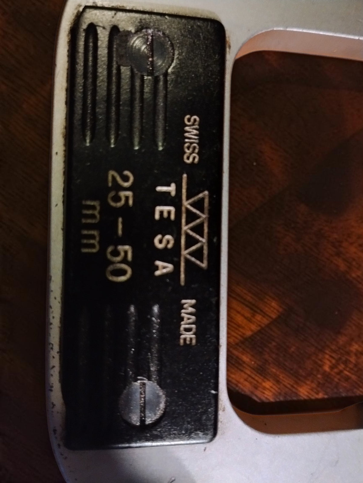 Vertical close-up of the black TESA plate showing the Swiss Made and 25–50 mm markings
