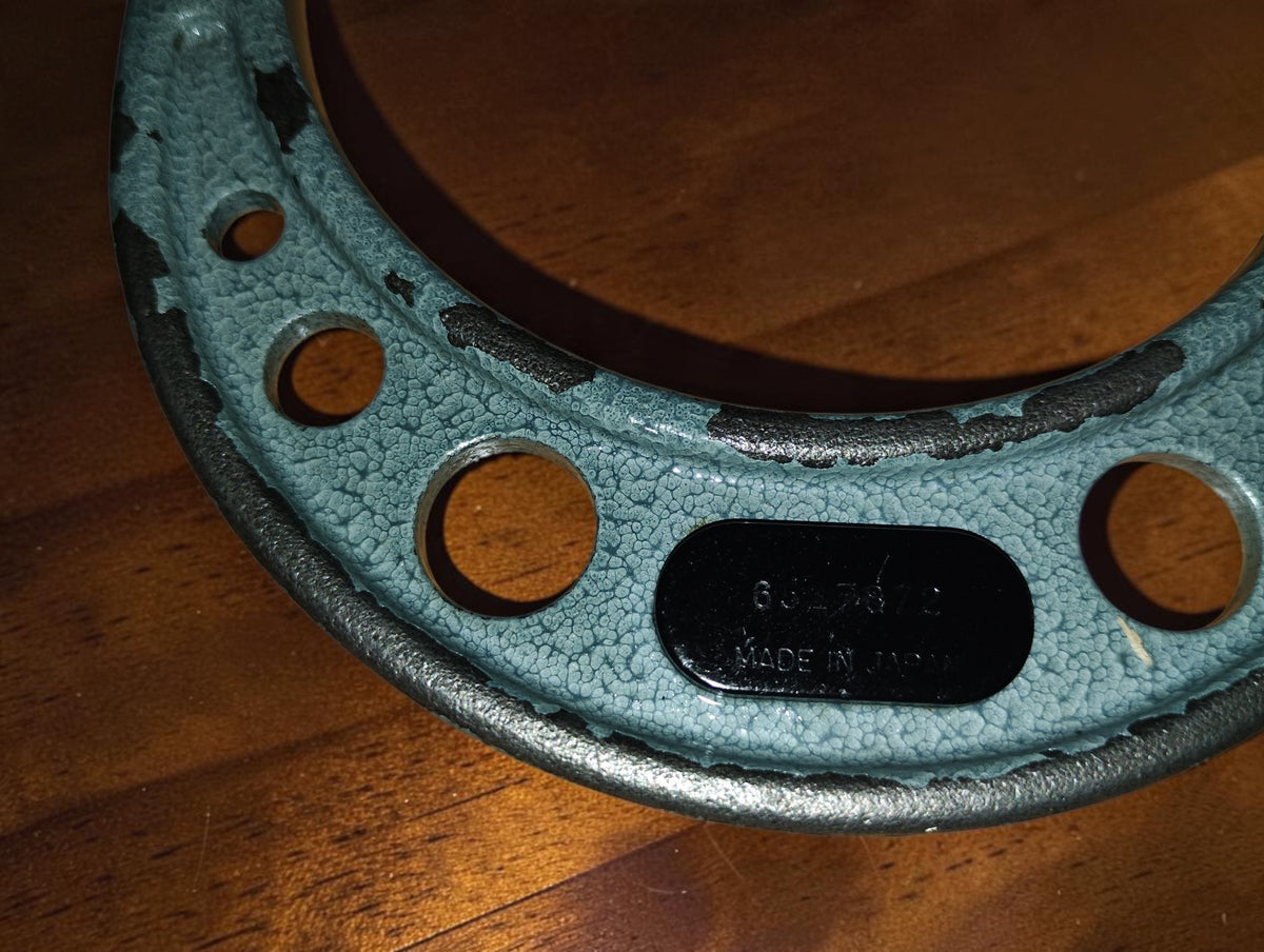 Detail van het merklabel en zichtbare verfslijtage op het frame van de Mitutoyo schijfmicrometer
