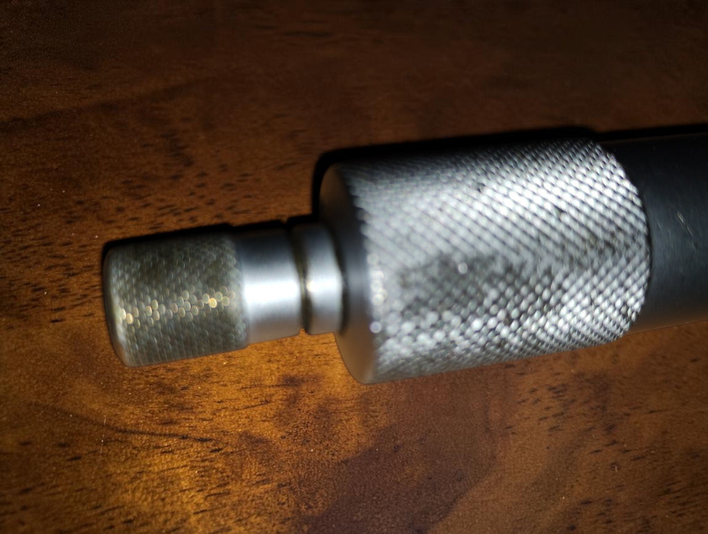 Detail van de geribbelde draaiknop en ratelknop van de Mitutoyo schijfmicrometer
