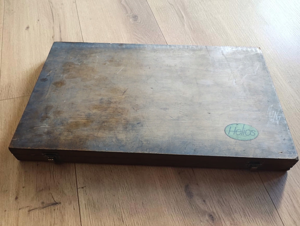 Gesloten houten kist met Helios-logo op het deksel

