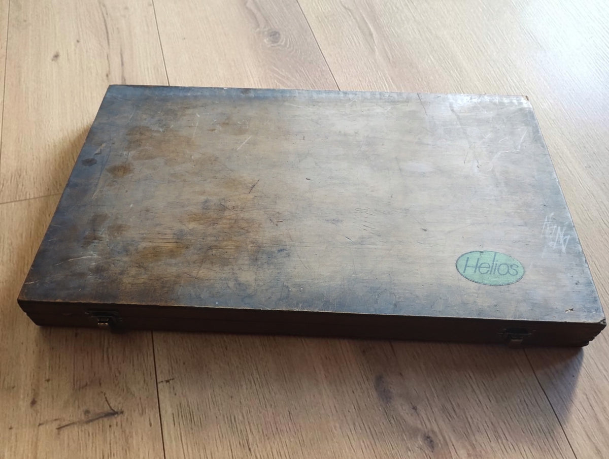 Gesloten houten kist met Helios-logo op het deksel
