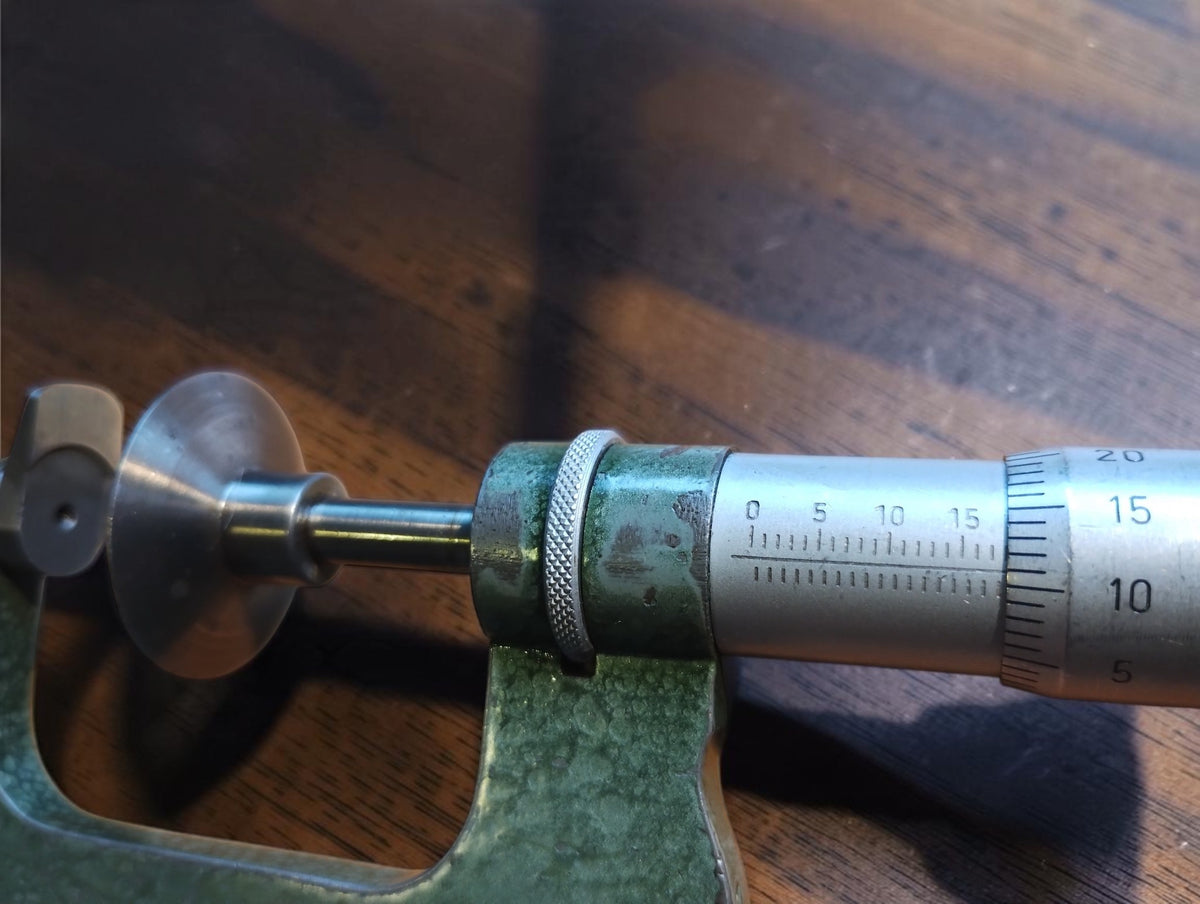 Close-up of the vintage disc micrometer showing the engraved scale, knurled collar and measuring faces
