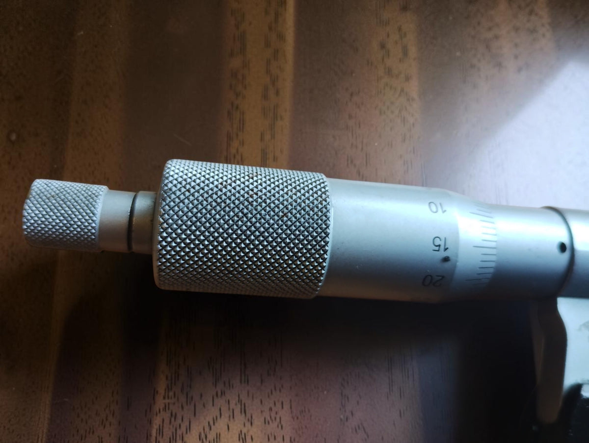 Close-up of the Mitutoyo micrometer’s knurled thimble, ratchet knob and engraved measuring scale.
