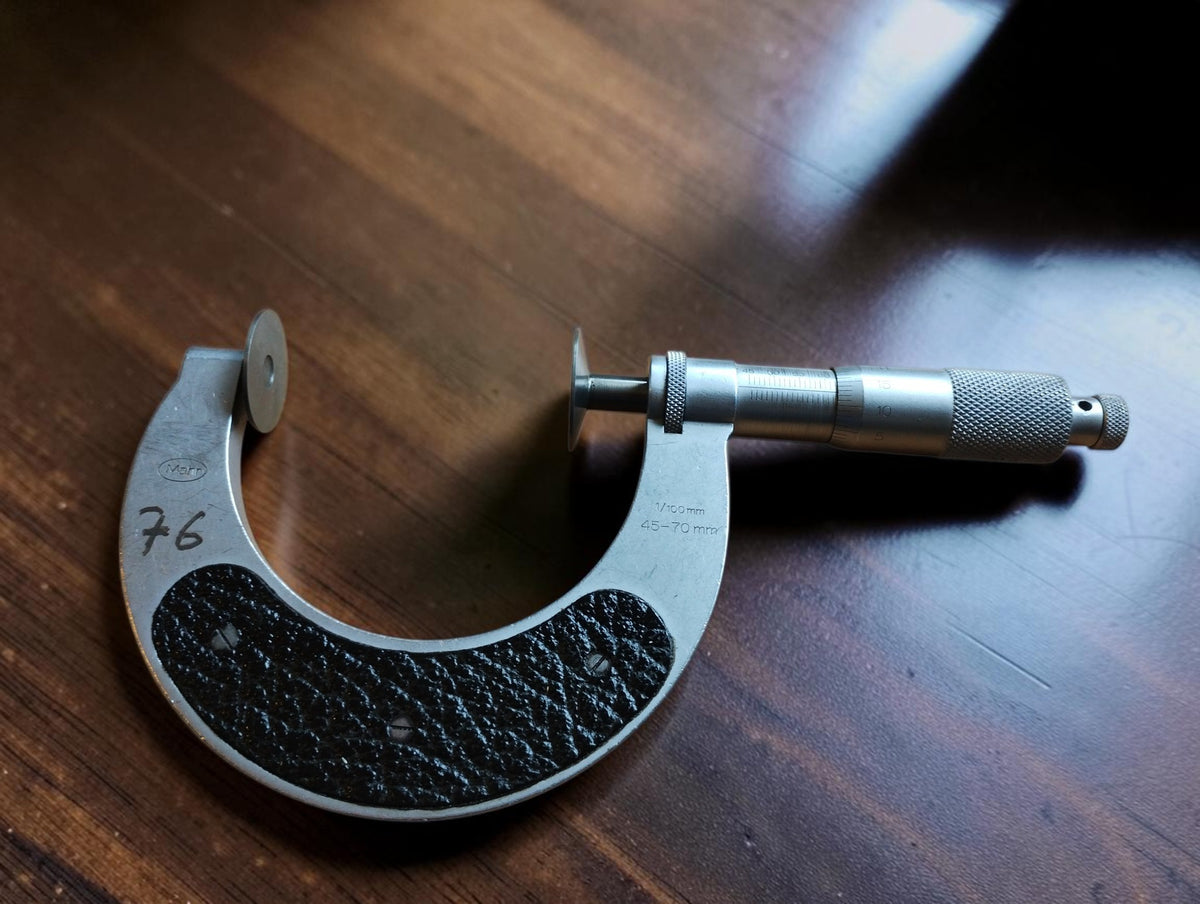 Vintage Mahr 45–70 mm disc micrometer with black grip panels and handwritten number 76.
