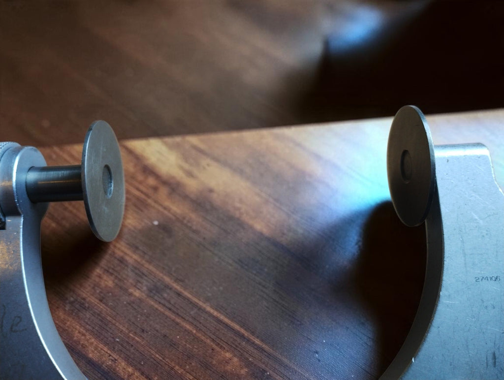 Close-up of the two opposing disc-shaped measuring faces on the vintage Mahr micrometer.
