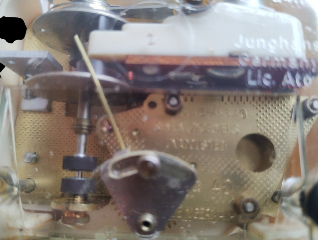 Close-up of the Junghans electronic clock movement beneath its transparent cover.
