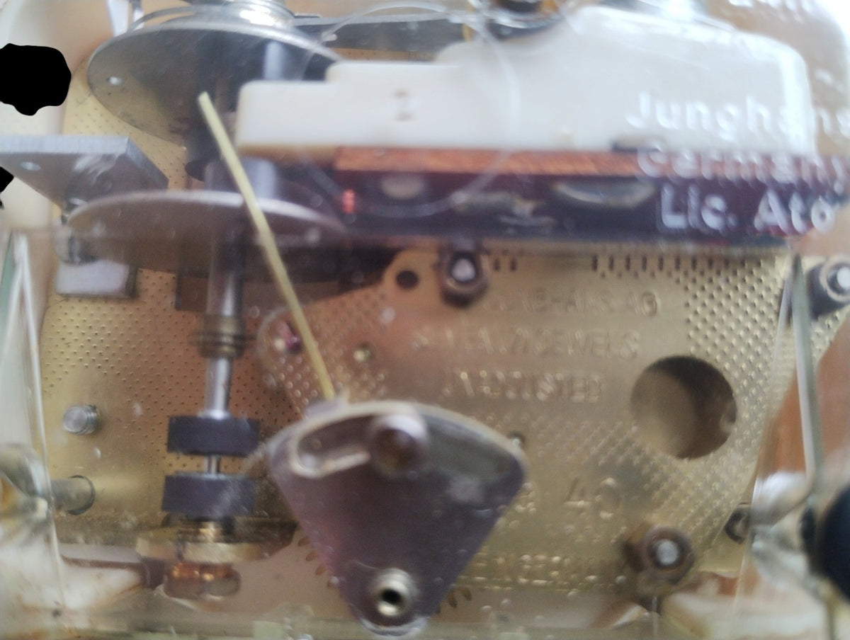 Close-up of the Junghans electronic clock movement beneath its transparent cover.
